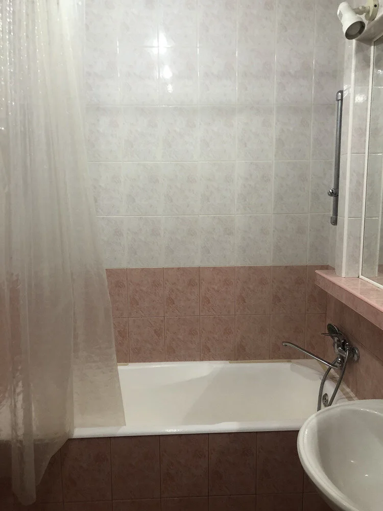 Altes Badezimmer mit Badewanne und alten rosa Wandfliesen vor der Vollsanierung